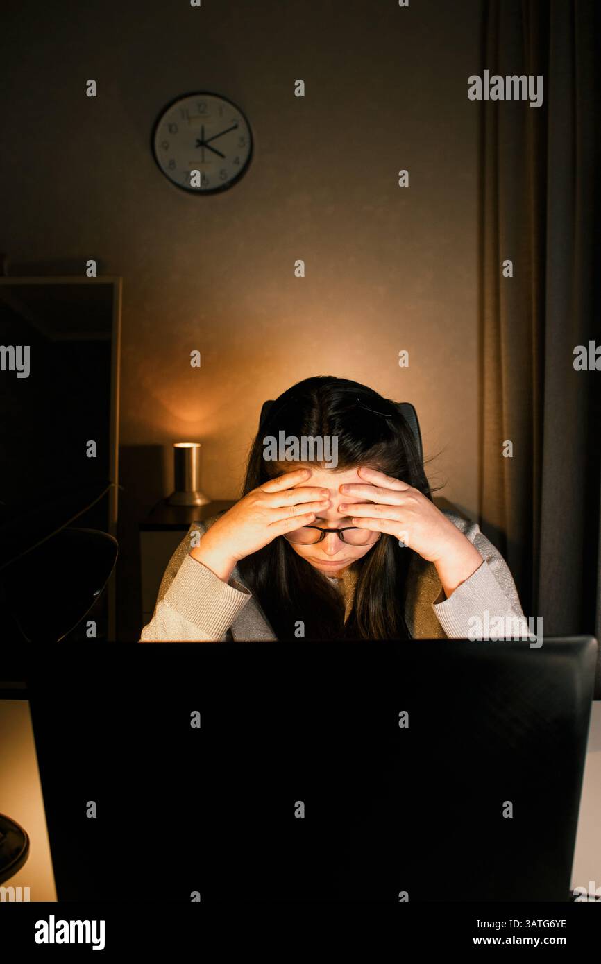 Una donna che lavora sodo lavora al computer nel suo ufficio domestico e cerca di risolvere i problemi di lavoro. Sentimento di disperazione e bruciati per problemi di lavoro Foto Stock