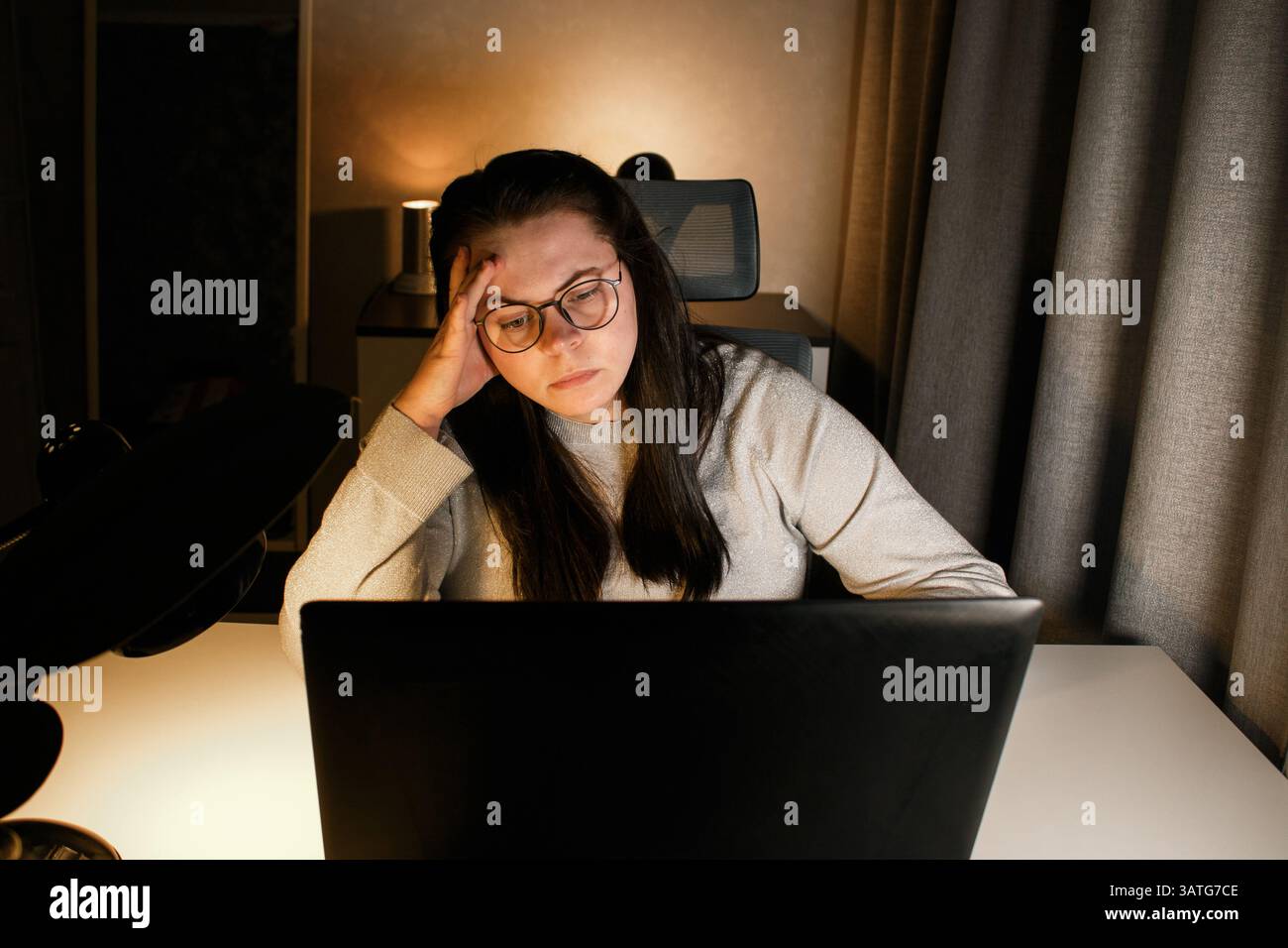 Una donna che lavora sodo lavora al computer nel suo ufficio domestico e cerca di risolvere i problemi di lavoro. Sentimento di disperazione e bruciati per problemi di lavoro Foto Stock