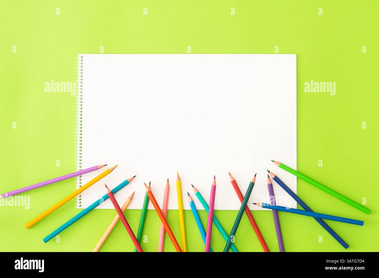 Pastelli con libro da disegno, matite colorate per pittura a secco su sfondo verde, design artistico di ritorno a scuola Foto Stock