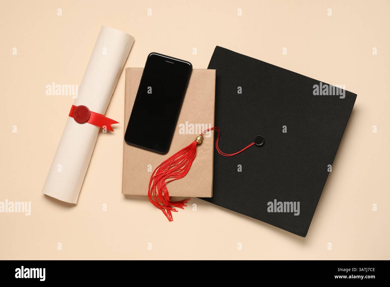 Bacheca con diploma, libro e telefono cellulare su sfondo giallo Foto Stock