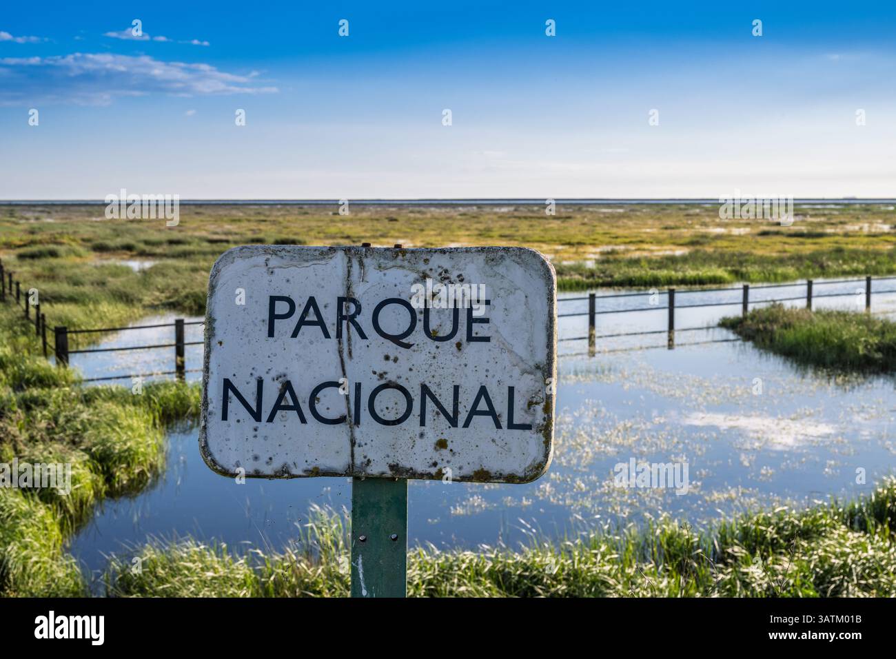 Recinzioni intempestive e un semplice cartello segnano l'ingresso alla riserva naturale di Doñana, che mostra lo splendido paesaggio delle zone umide. Foto Stock