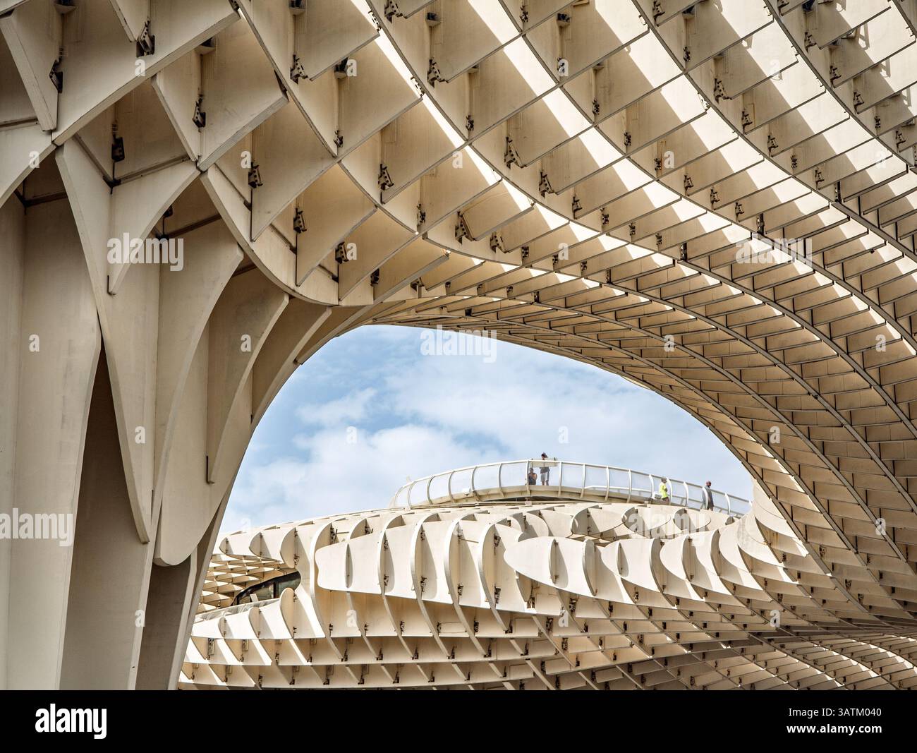 I visitatori ammirano l'intricata struttura a reticolo del Metropol Parasol di Siviglia, che mostra un design moderno contro un cielo nuvoloso. Foto Stock