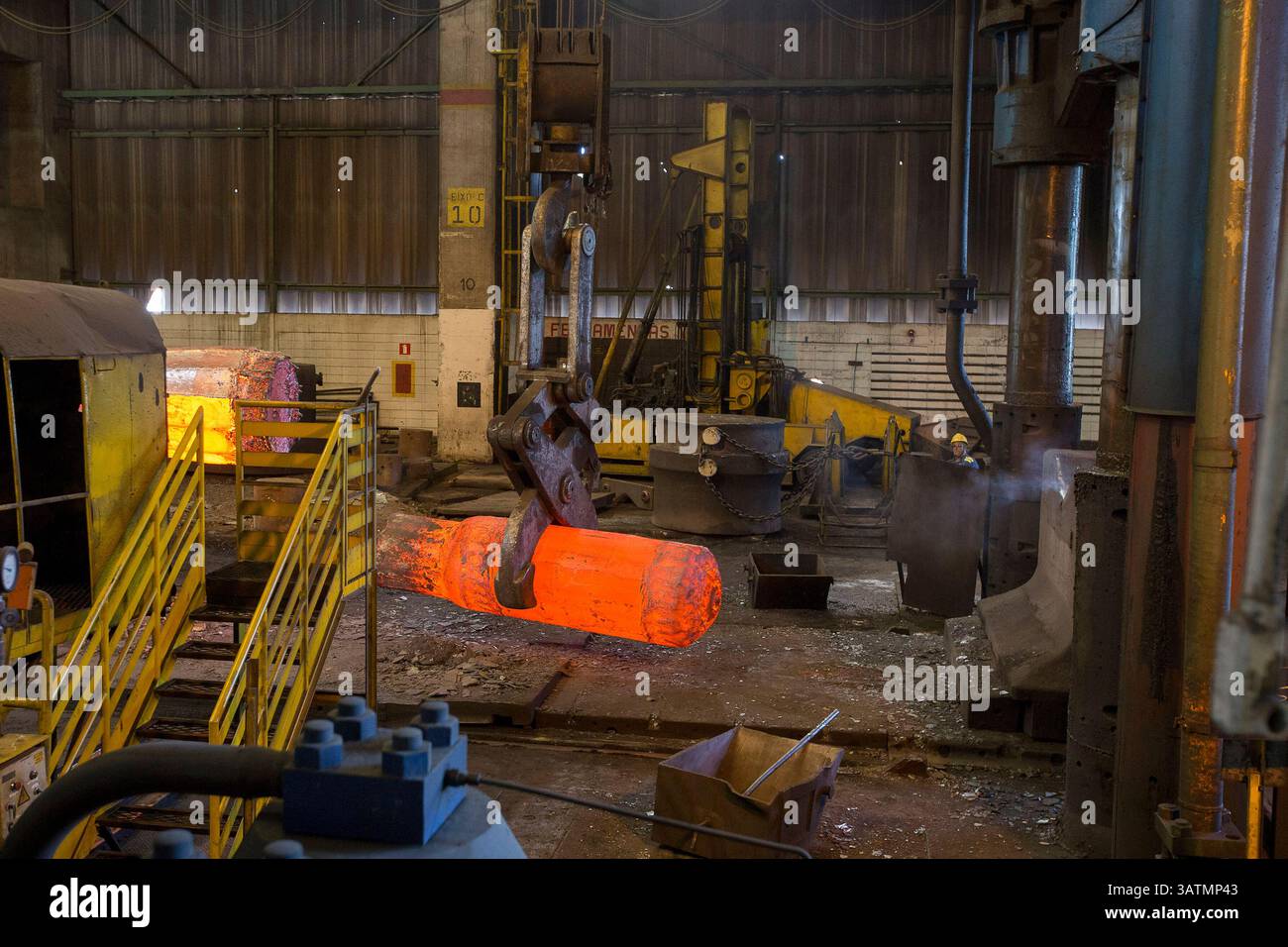 Stato di San Paolo, Brasile - 09 aprile 2018 - fucinatura metallica. il martello idraulico forma la billetta calda rossa. la produzione di componenti ad alta tecnologia. Foto Stock