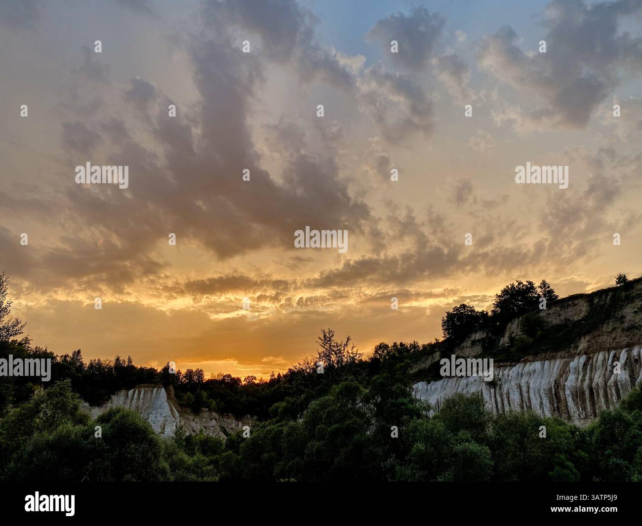 Tramonto su bianche scogliere di gesso e colline boscose con un suggestivo cielo serale Foto Stock