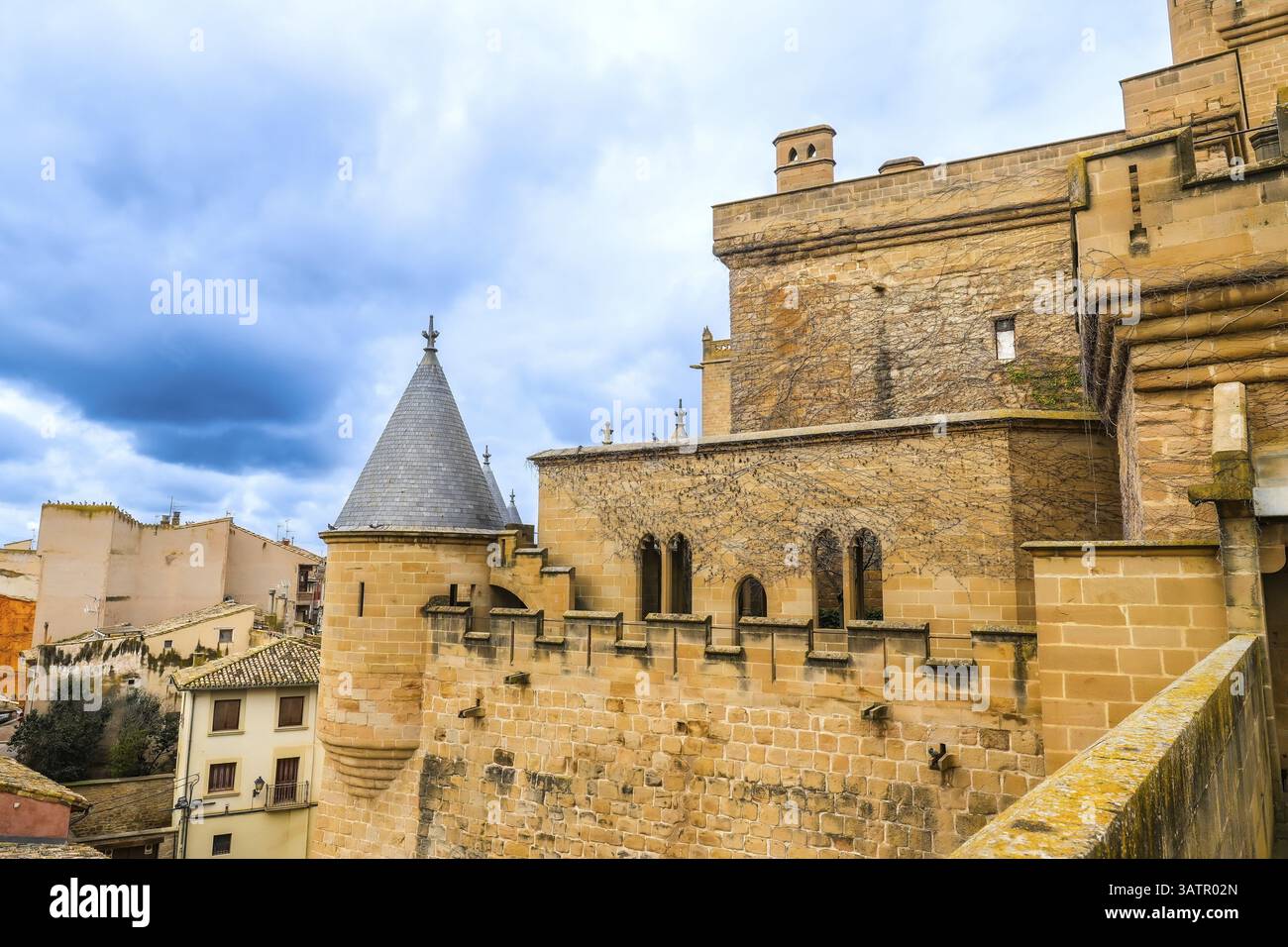 Maestoso palazzo reale di olite che sorge sopra la città, con le sue imponenti torri, le mura fortificate e l'architettura medievale sotto un cielo nuvoloso Foto Stock