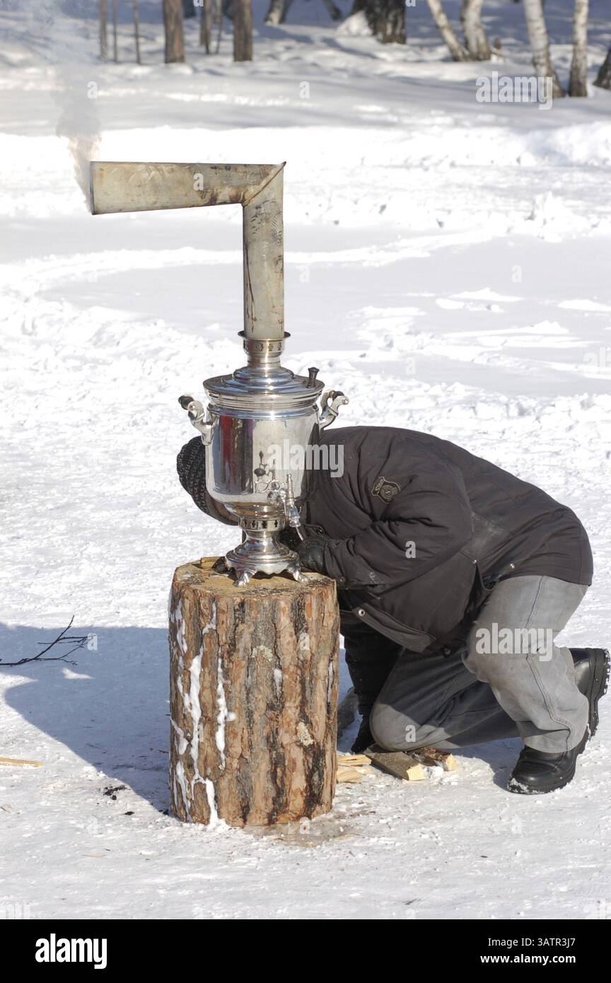 ULAN-UDE, RUSSIA - FEBBRAIO 28: Un uomo accende un vecchio samovar classico nell'ultimo giorno del festival dei pancake, quando la gente mangia pancake con tè caldo, febbraio Foto Stock