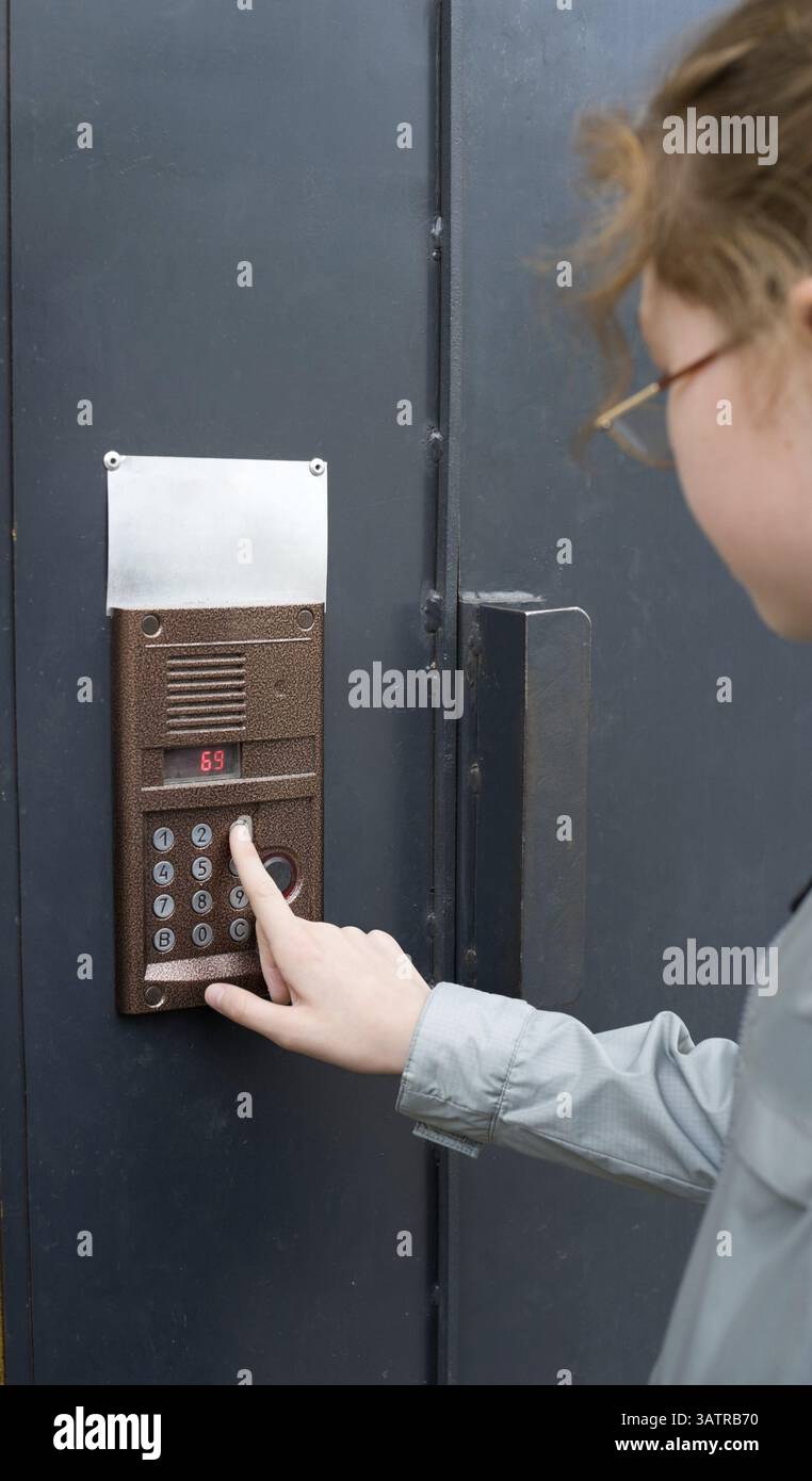 Una ragazza compone le cifre su un interfono della porta d'ingresso Foto Stock