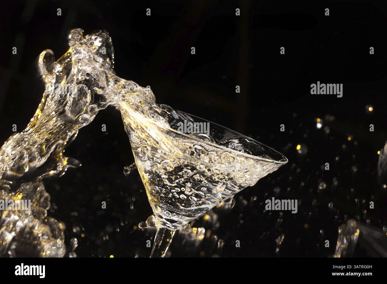 Versamento di liquido in vetro su un nero di sfondo per studio Foto Stock