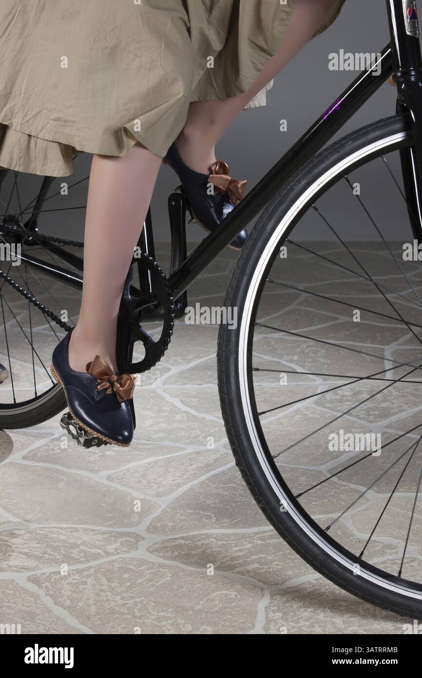 Gambe di donna e bicicletta su uno sfondo di studio fatto di pietre artificiali Foto Stock