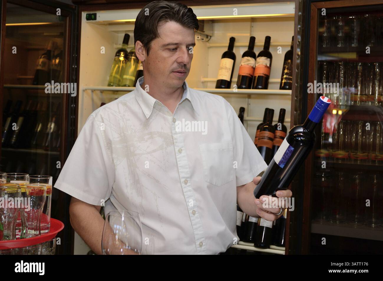 Il cameriere legge l'etichetta su una bottiglia di vino rosso Foto Stock