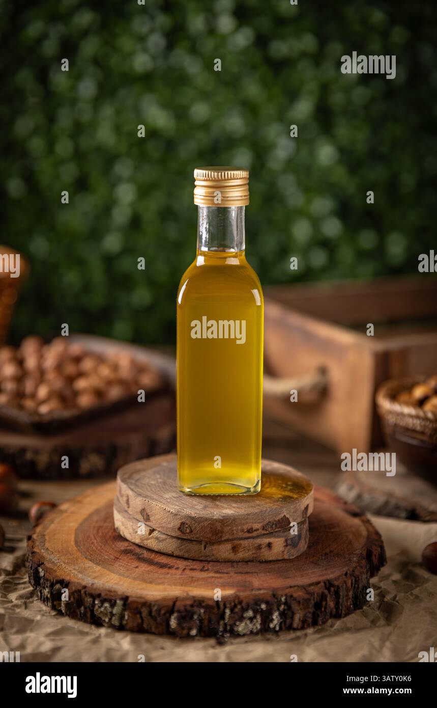 L'olio di noci di macadamia in una bottiglia di vetro si trova su rustici sottobicchieri in legno Foto Stock