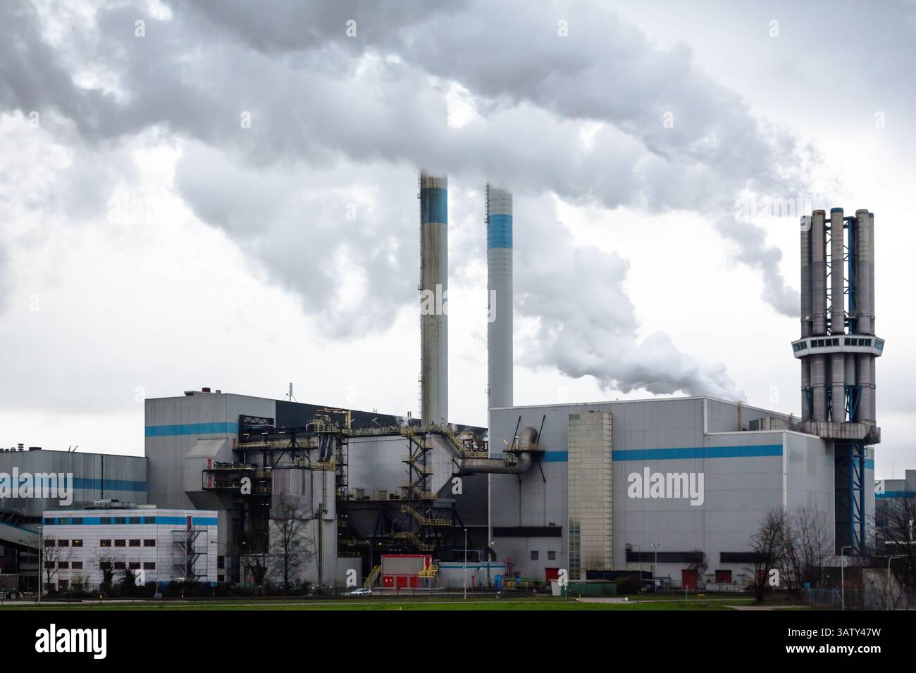Un impianto industriale con camini da cui fuoriesce fumo denso in un cielo nuvoloso. Inquinamento ambientale da parte dell'industria. Foto Stock