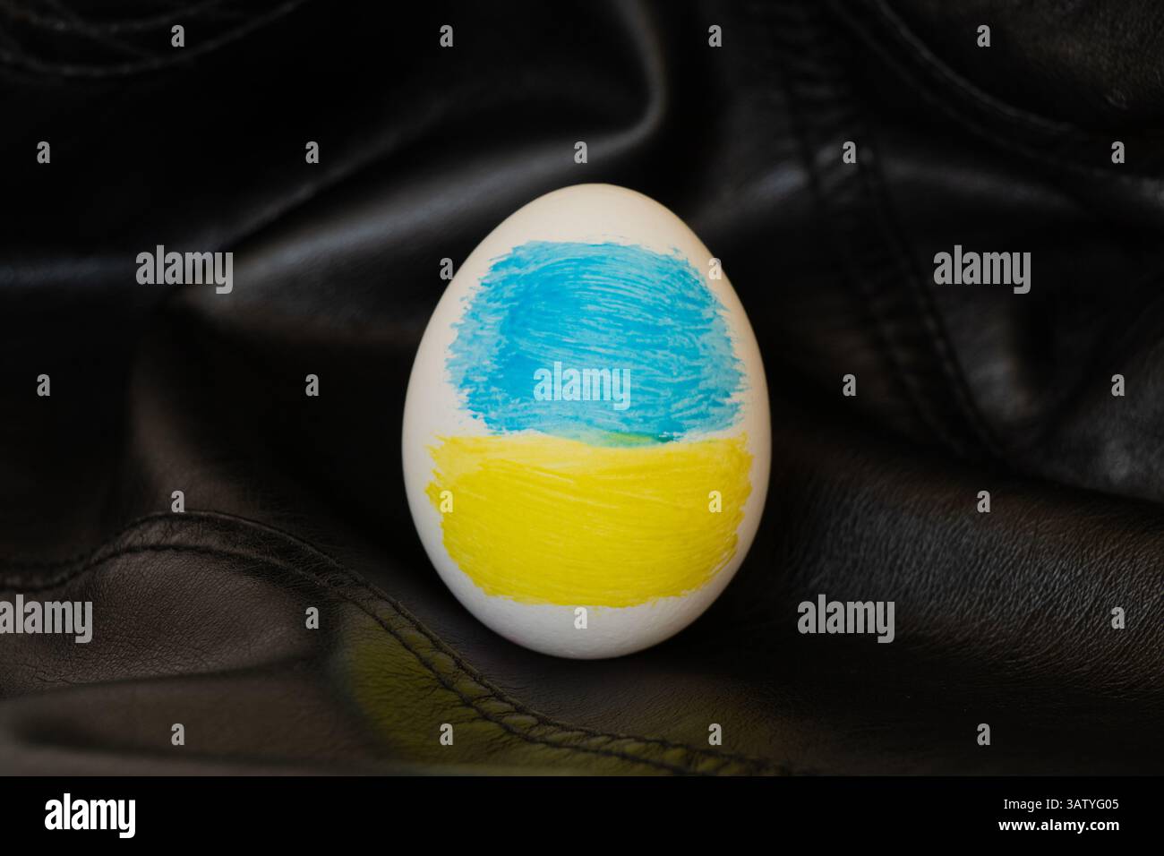 Uovo di Pasqua con bandiera Ucraina dipinta su sfondo di pelle scura, celebrazione pasquale in Ucraina Foto Stock