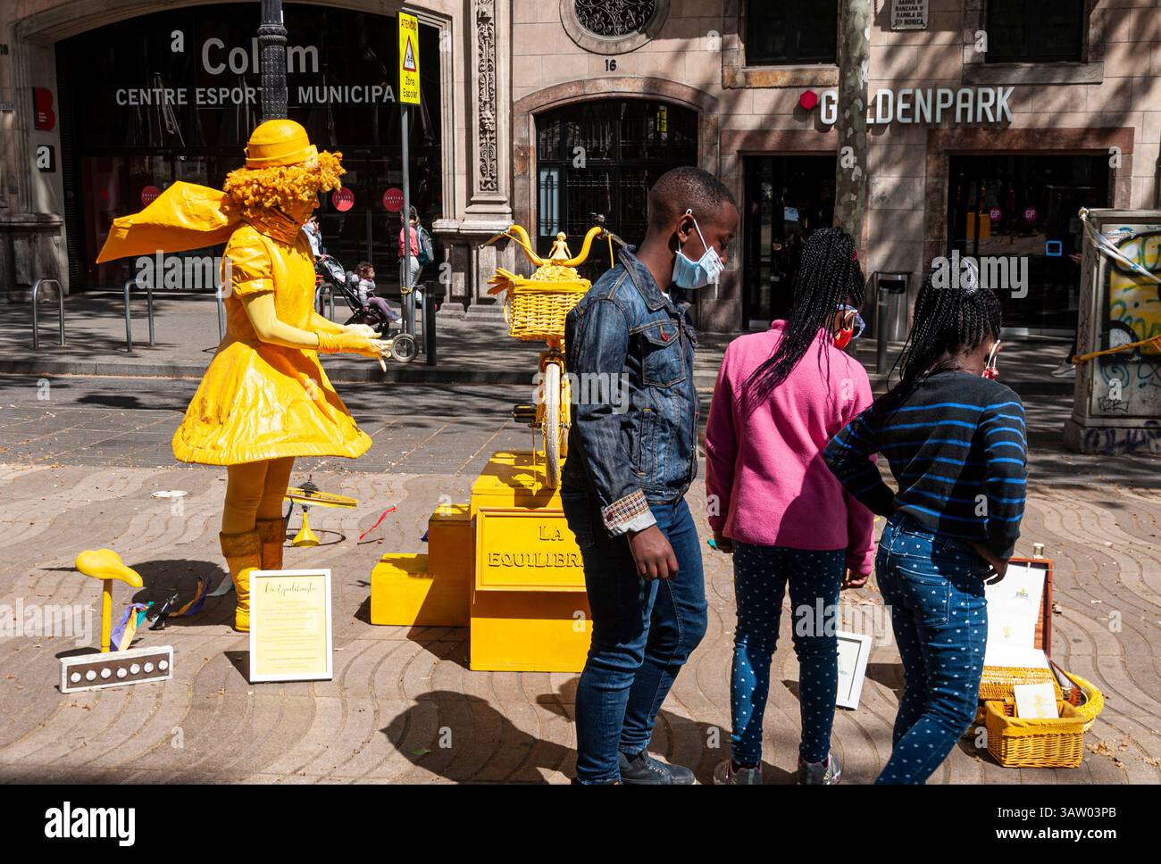 Adolescenti neri sorridenti con maschera facciale accanto alla statua di una donna che interpreta la Rambla, Barcellona, Spagna Foto Stock