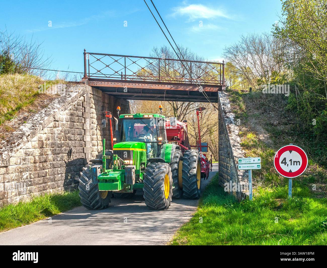 Trattore John Deere 7810 con macchina combinata Kuhn Venta AL 402 per perforazione e erpice che attraversa un ponte basso e stretto - Francia centrale. Foto Stock