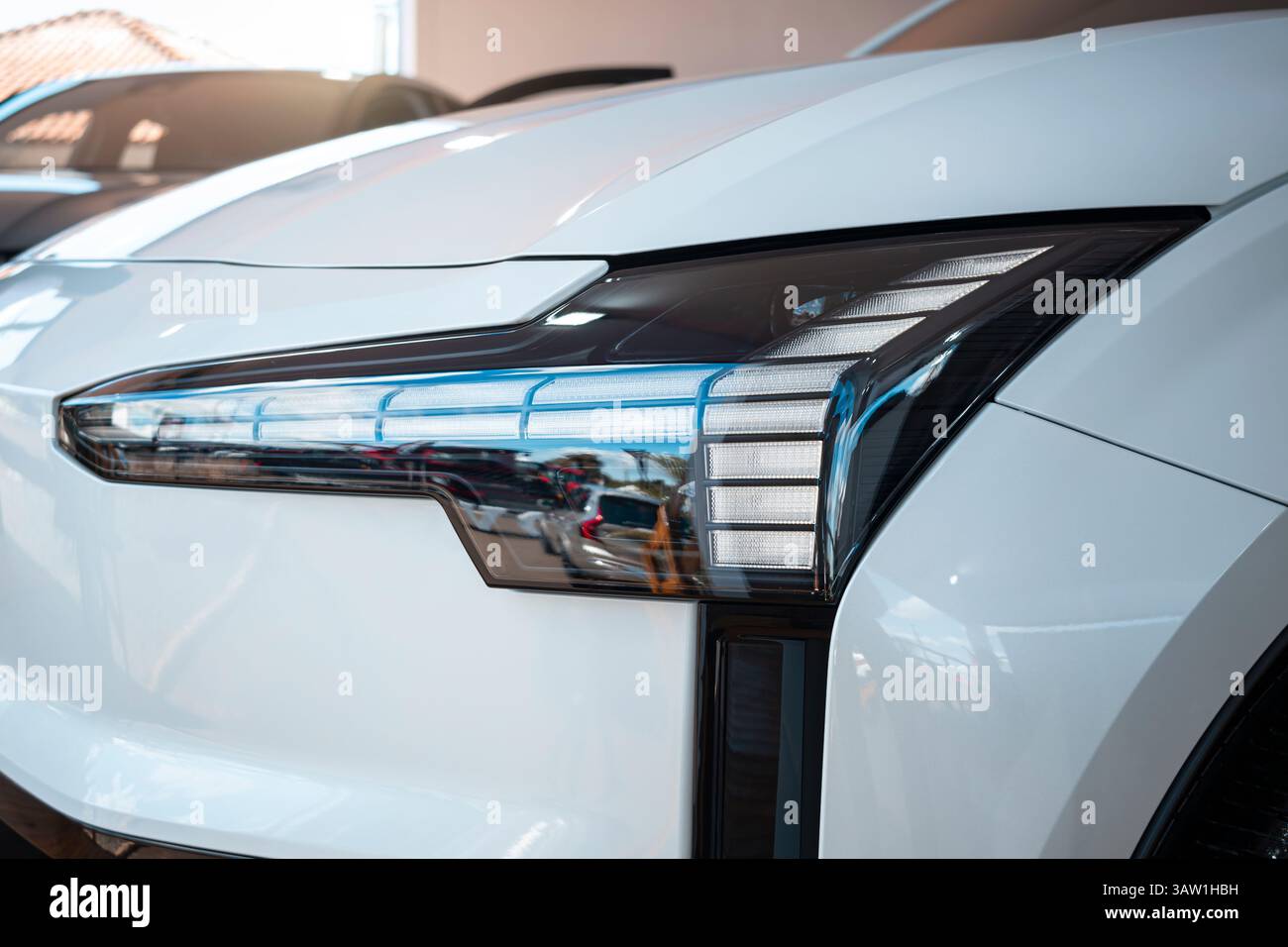 Faro anteriore di un'auto bianca con design futuristico e linee accattivanti, che mettono in risalto la raffinatezza e la tecnologia dell'auto. Foto Stock