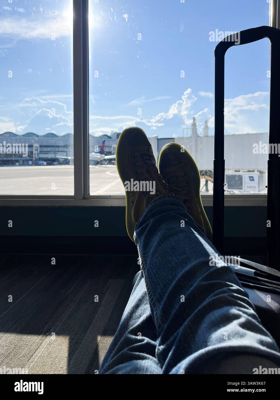 Una persona si sta sdraiando con le gambe incrociate e i piedi in alto davanti a una finestra. La persona indossa un paio di scarpe gialle Foto Stock Una persona si sta sdraiando con le gambe incrociate e i piedi in alto davanti a una finestra. La persona indossa un paio di scarpe gialle Foto Stock