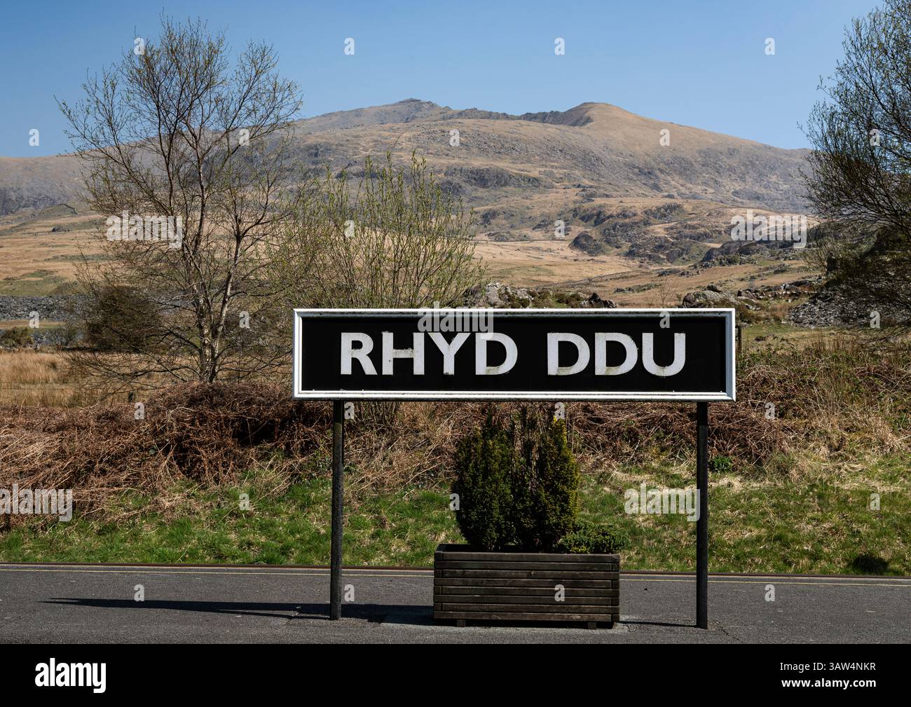 Cartello della stazione ferroviaria di Rhyd DDU sulla Welsh Highland Railway; campagna aperta e montagna Yr Wyddfa o Snowdon sullo sfondo Foto Stock