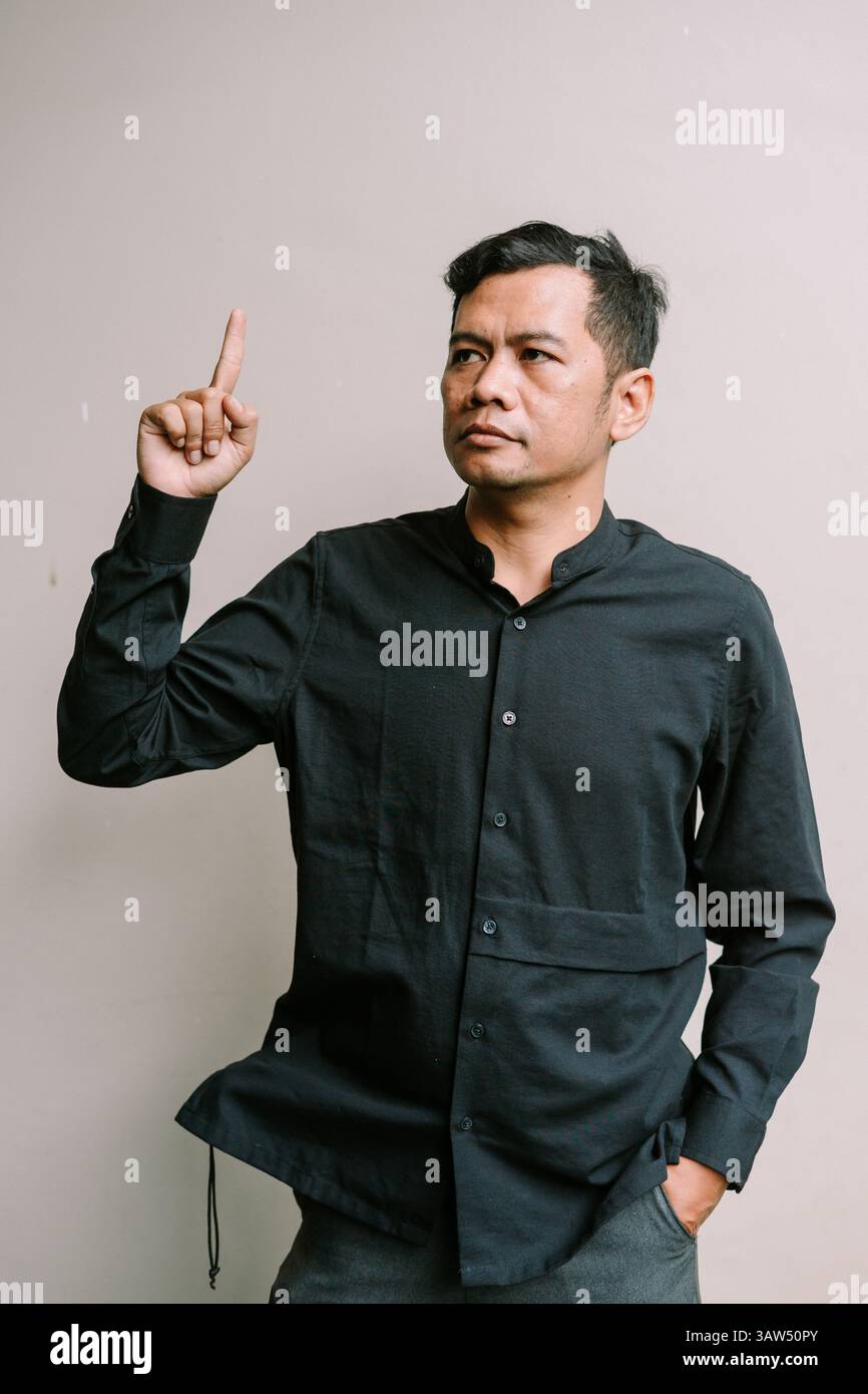 Un uomo asiatico punta verso l'alto, forse rappresentando una soluzione o un'ispirazione, copia lo spazio disponibile Foto Stock