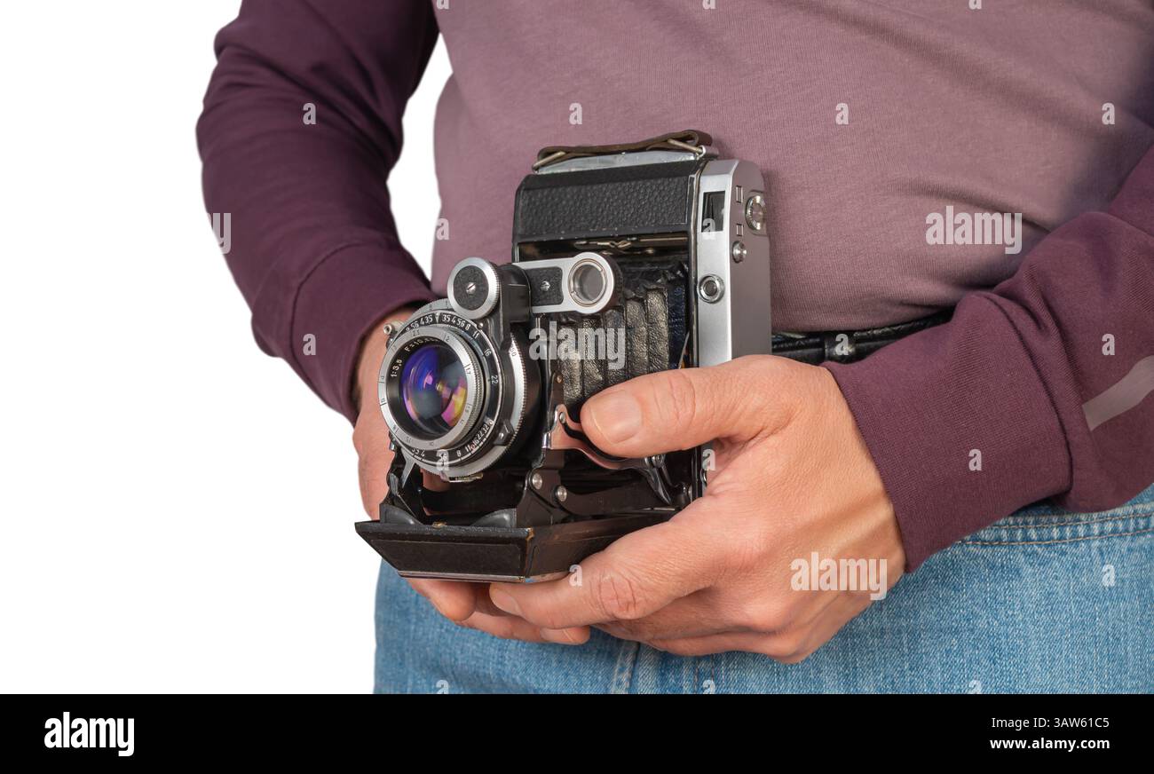 Persona che tiene in mano una fotocamera vintage all'aperto, che mette in luce la passione per la fotografia con particolare attenzione al design classico e ai dettagli. Foto Stock