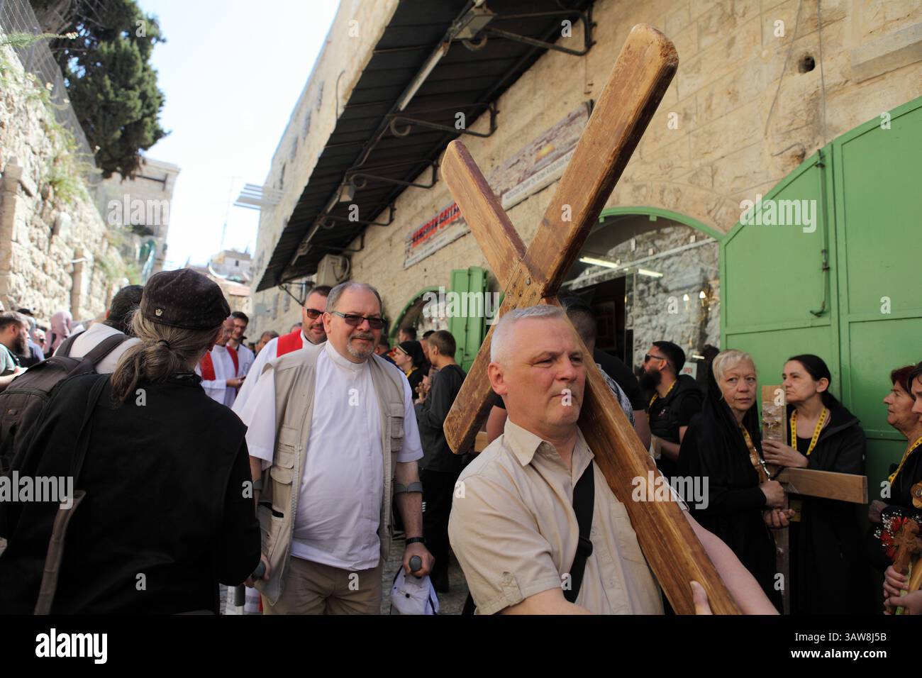 Pellegrini cristiani con una croce, cammina in una processione del venerdì Santo vicino all'Arco Ecce Home sulla via dolorosa nella città vecchia di Gerusalemme. Foto Stock