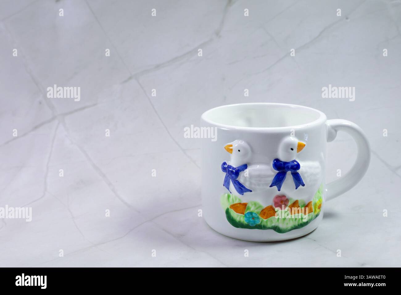Una tazza in ceramica bianca con due anatre è attualmente appoggiata su un tavolo Foto Stock