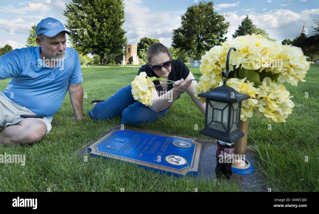 6 giugno 2016 - Overland Park, KS, USA - Greg Smith, Left, guarda come Missy Smith adatta i fiori mentre visita la tomba della loro figlia Kelsey Smith nel nono anniversario della scoperta del suo corpo lunedì 6 giugno 2016, in Kansas. Il Kelsey Smith Act, che permette alle forze dell'ordine di accedere al segnale GPS nei cellulari, e' fallito al Congresso il mese scorso. Il giallo dei fiori ricorda a Missy il vestito da ballo di Kelsey -- il vestito in cui è stata sepolta. (Immagine di credito: © Shane Keyser/TNS tramite filo ZUMA) Foto Stock