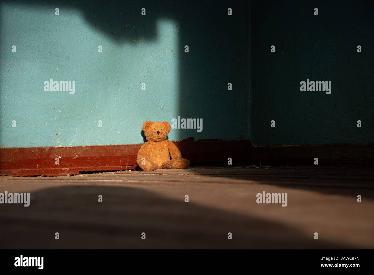Un morbido orsacchiotto marrone giace abbandonato sul pavimento in una vecchia casa abbandonata in Ucraina, un giocattolo abbandonato Foto Stock