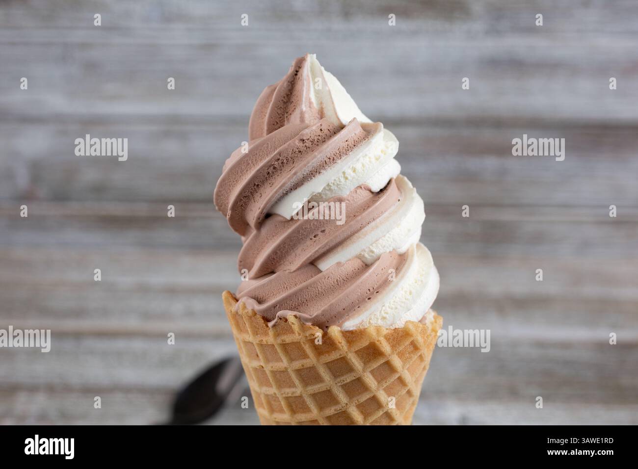 Vista ravvicinata di un turbinio di vaniglia al cioccolato allo yogurt congelato su un cono di waffle. Foto Stock