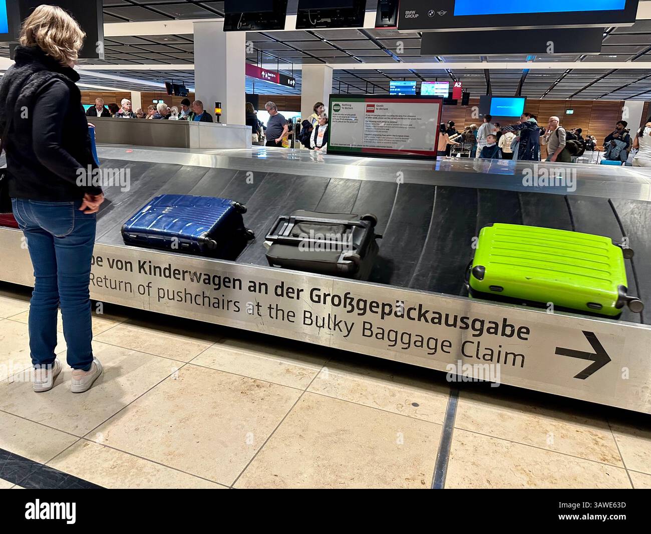 Donna che aspetta il suo bagaglio al ritiro bagagli dell'aeroporto BER Schönefeld, Berlino, Germania Foto Stock