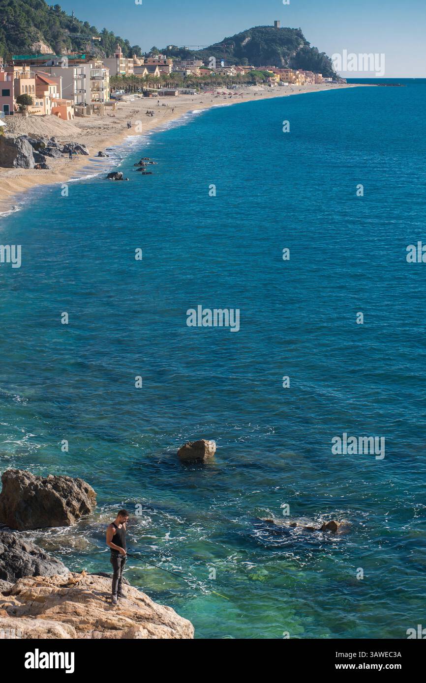 La spiaggia di Varigotti. Spiaggia di Varigotti. Varigotti è una frazione del comune di finale Ligure, in Liguria. Uomo che pesca con una canna da pesca in primo piano. Foto Stock