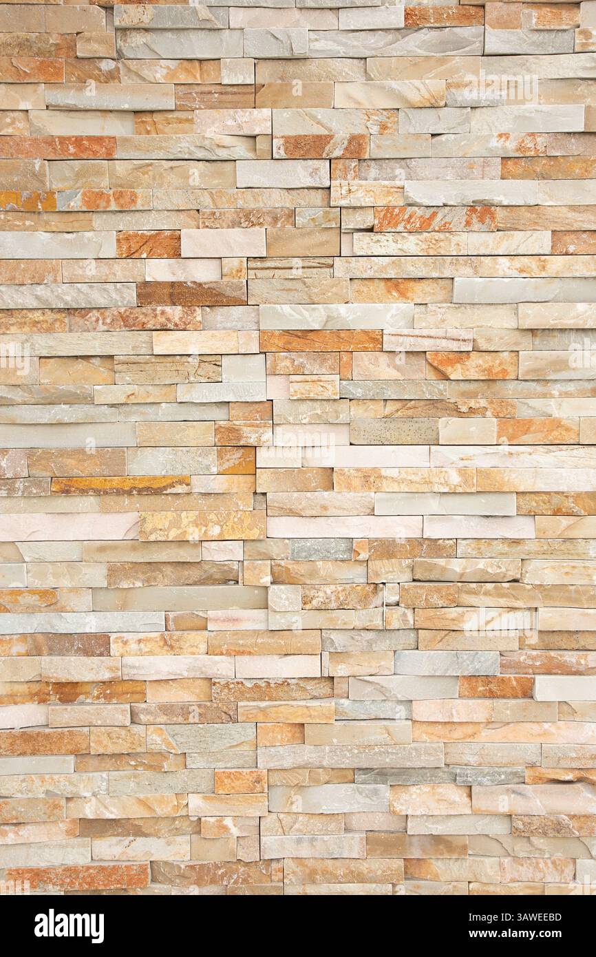 Una vista di una facciata murale di pietre abbronzate orizzontali e beige, come sfondo. Foto Stock