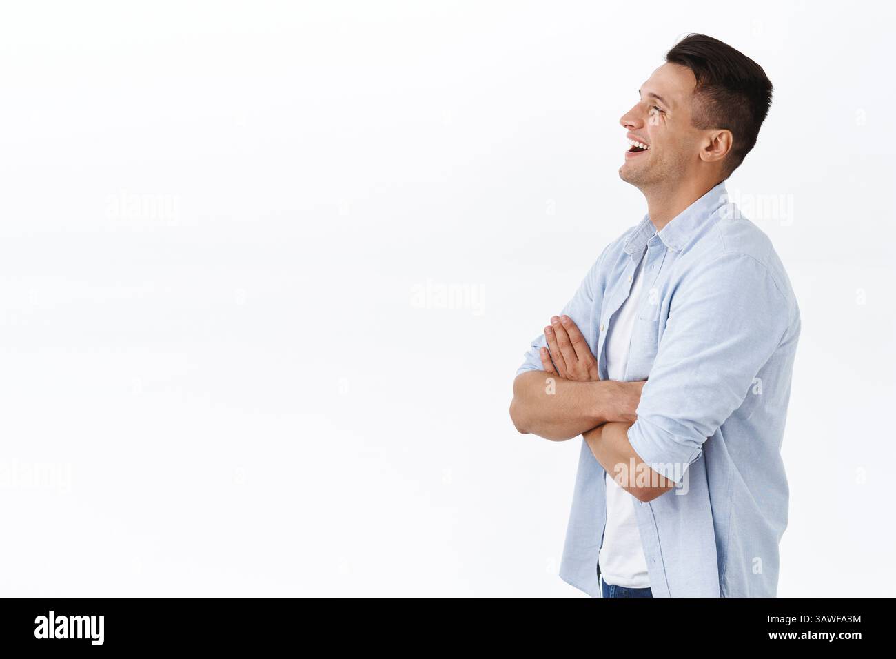 Profilo ritratto di bel ragazzo di famiglia felice adulto in camicia, croce mani sul petto, ridendo e sorridendo compiaciuto, guardando a sinistra spazio vuoto a un certo punto Foto Stock
