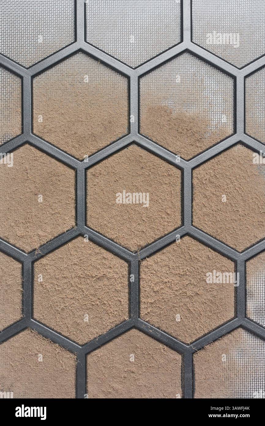 primo piano del filtro dell'aria ostruito del telaio del computer su sfondo full frame, schermo a maglia fine con griglia esagonale intrappolata con uno strato di polvere e sporco Foto Stock