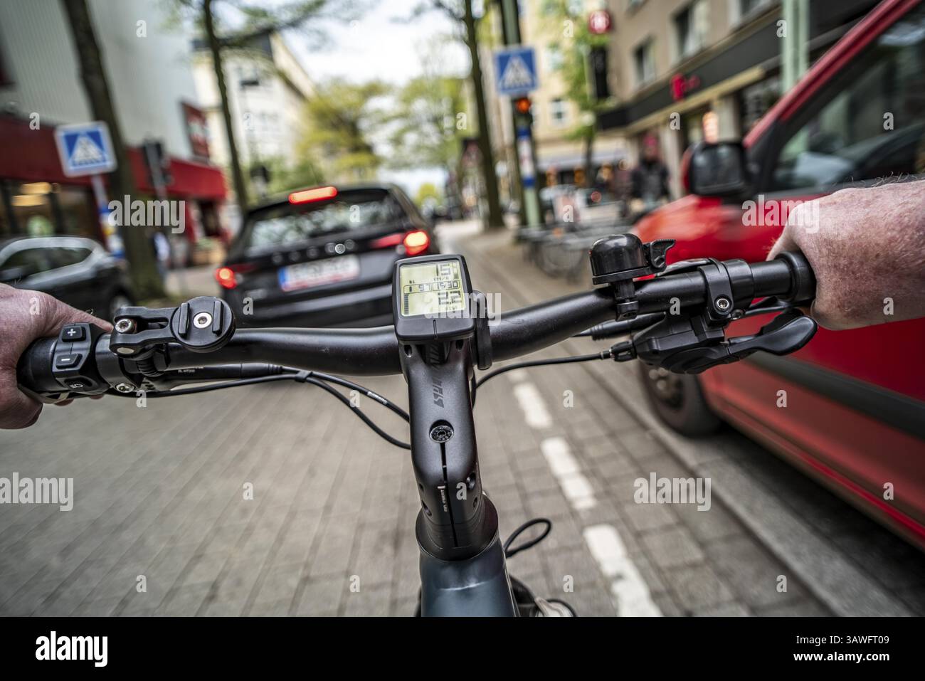 Andare in bicicletta in città, in centro, in pista ciclabile, le biciclette hanno la priorità, il traffico a due corsie con auto parcheggiate su entrambi i lati, la prospettiva dei ciclisti, ES Foto Stock