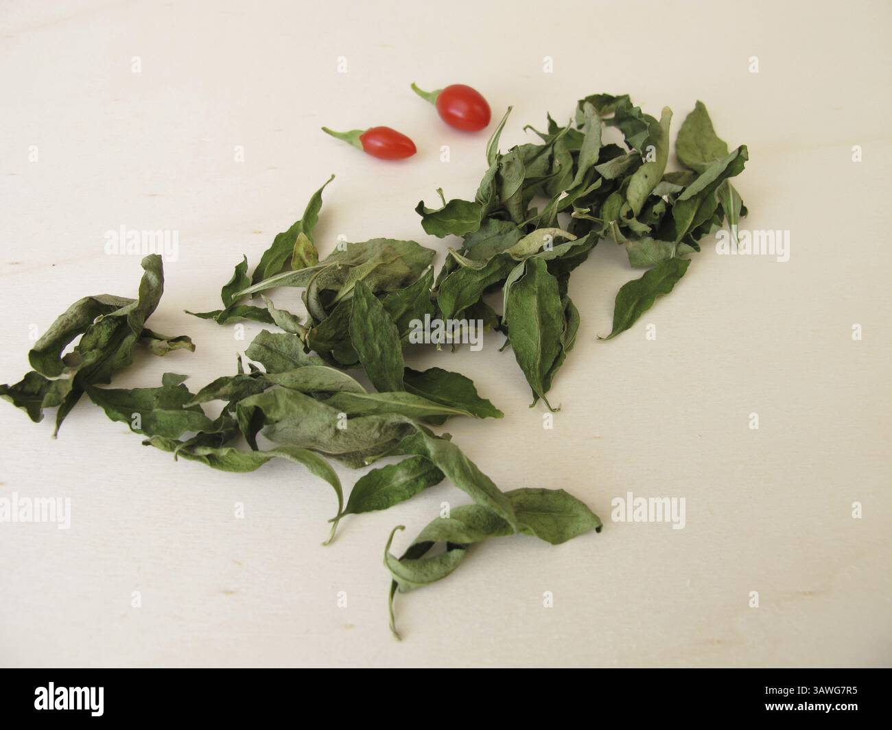 Foglie di goji essiccate su una tavola di legno Foto Stock