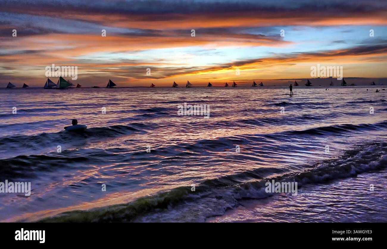 I vacanzieri in bagno, le barche a vela e le imbarcazioni da diporto popolano le acque calme intorno alla famosa isola del resort Boracay in Malay, Aklan, Filippine. Foto Stock