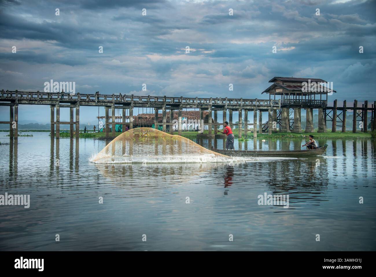 Pescatore che lancia una rete da pesca sul lago Taungthaman accanto al ponte U Bein vicino ad Amarapura in Myanmar Foto Stock