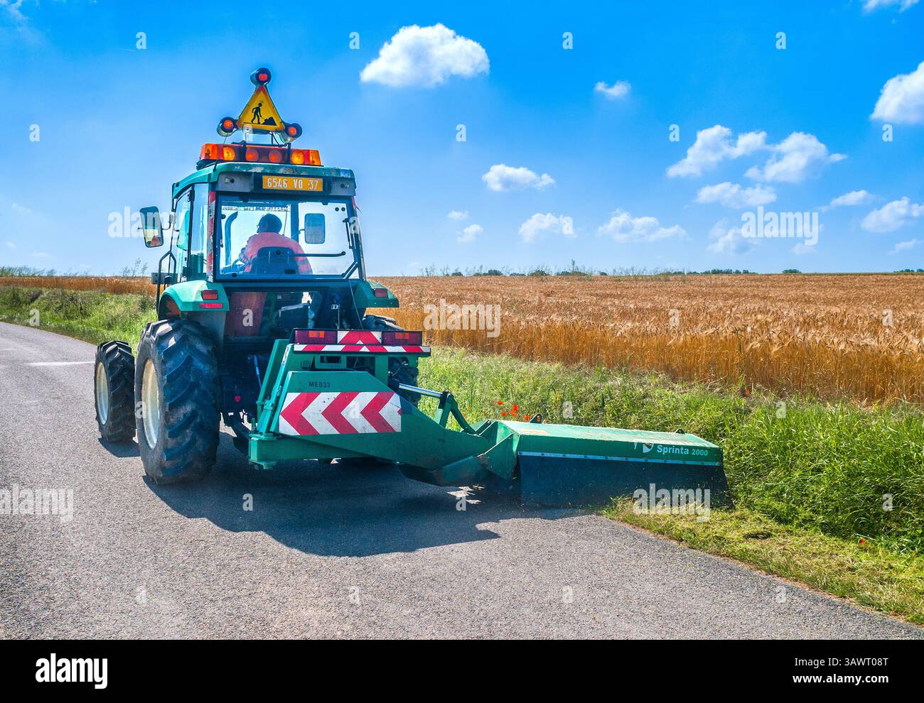 Trattore comune dotato di una falciatrice Noremat Sprinta 2000 Verge che taglia un'orlo stradale in campagna - Francia centrale. Foto Stock