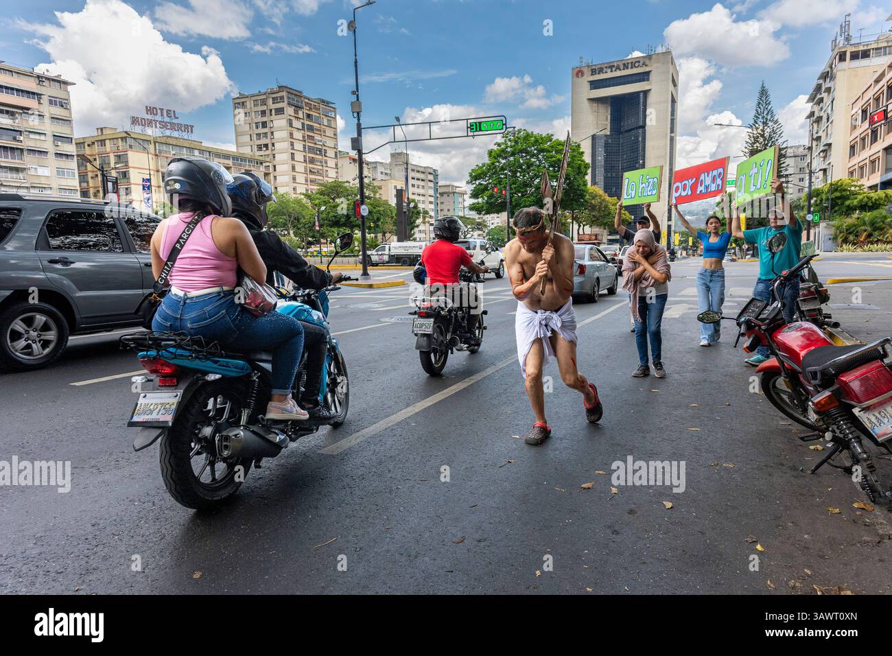 Un uomo in una rappresentazione di Gesù Cristo attraversa un incrocio su una strada a Caracas. Foto Stock