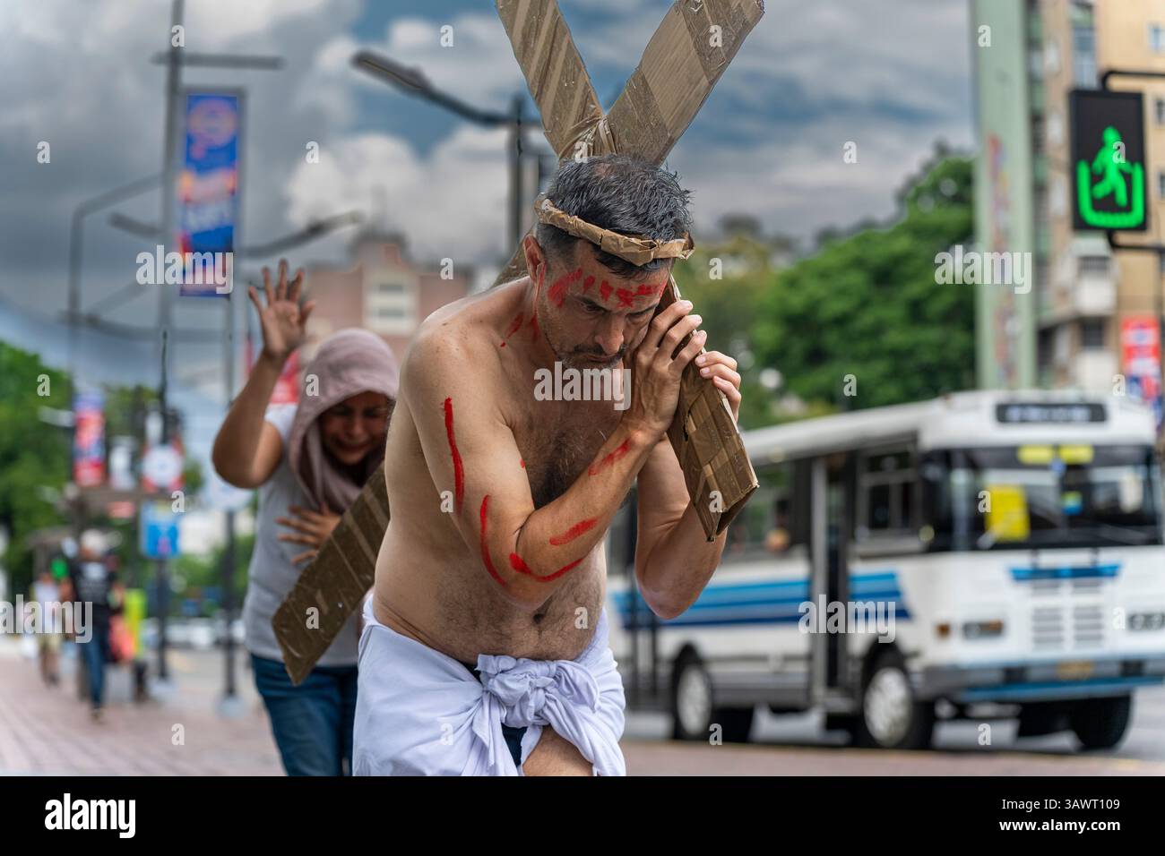 Un uomo in una rappresentazione di Gesù Cristo attraversa un incrocio su una strada a Caracas. Foto Stock
