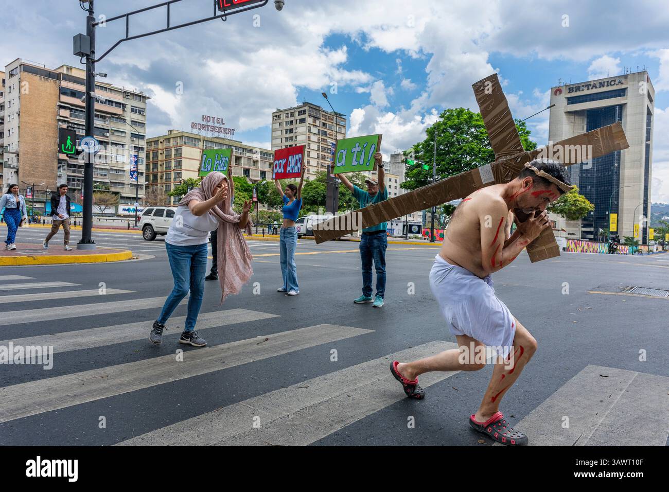 Un uomo in una rappresentazione di Gesù Cristo attraversa un incrocio su una strada a Caracas. Foto Stock