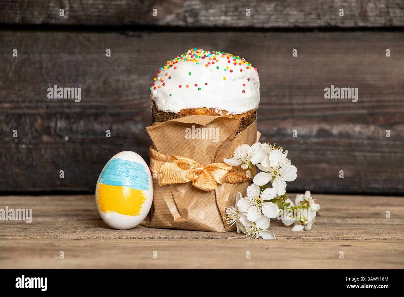 Uovo di Pasqua con una bandiera dipinta dell'Ucraina, torta di Pasqua e un ramo di ciliegia in fiore su un tavolo di legno, Pasqua in Ucraina Foto Stock