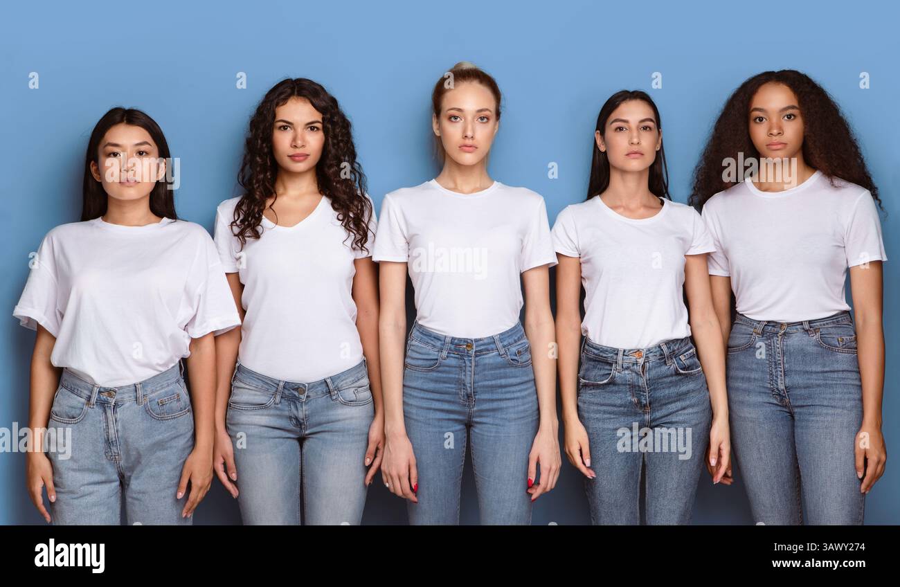 Gruppo di donne multiculturali gravi che posano su sfondo blu, Panorama Foto Stock