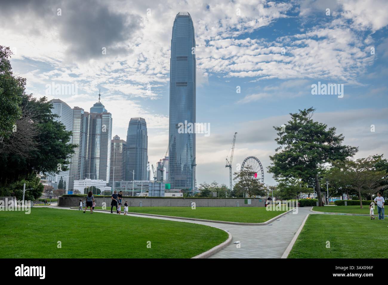 Hong Kong. Cina- 03.03.2025. Persone che si godono una passeggiata sul Tamar Park con i grattacieli distratti Central sullo sfondo. Foto Stock