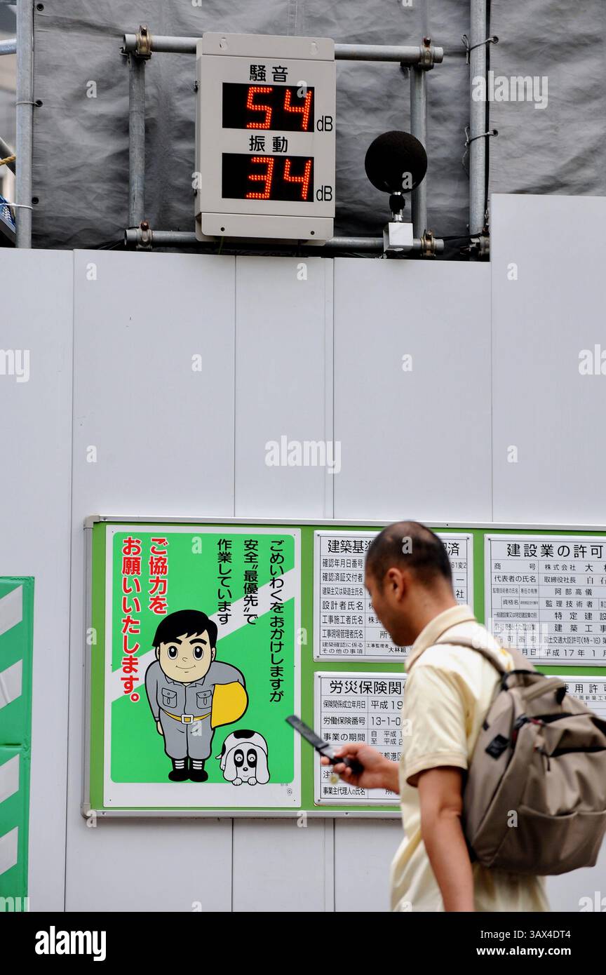Un uomo passa davanti a un sensore elettronico che misura i livelli di rumorosità e vibrazioni in un cantiere nel centro di Tokyo, Giappone, 9 luglio 2008. la cacofonia del no Foto Stock
