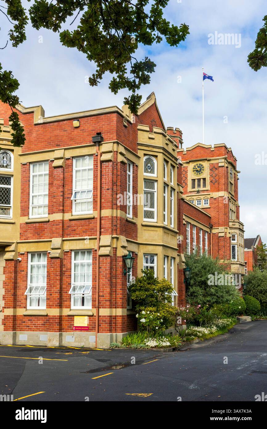 Edificio storico in mattoni con torre dell'orologio e bandiera neozelandese al King's College di Auckland, nuova Zelanda Foto Stock