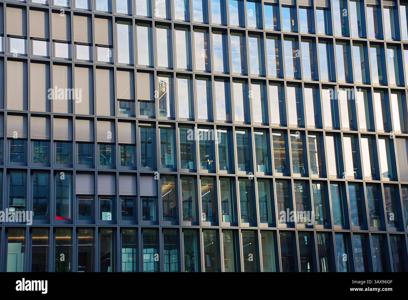 Primo piano di un moderno edificio per uffici con finestre simmetriche in vetro e cornici in acciaio che riflettono il paesaggio urbano. Dettagli dell'architettura urbana Foto Stock