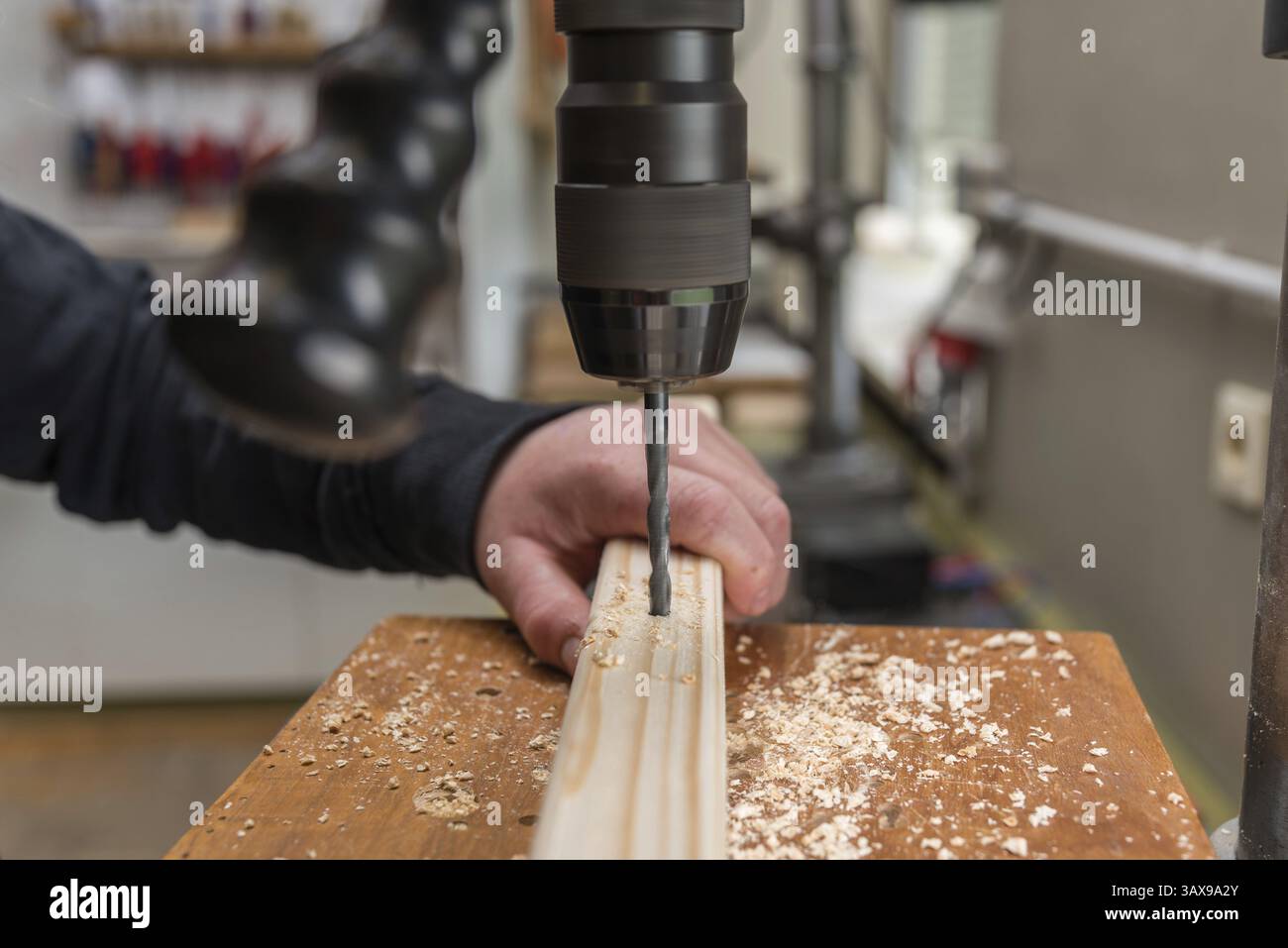 Carpentiere esegue un foro nel legno con un trapano elettrico - primo piano Foto Stock