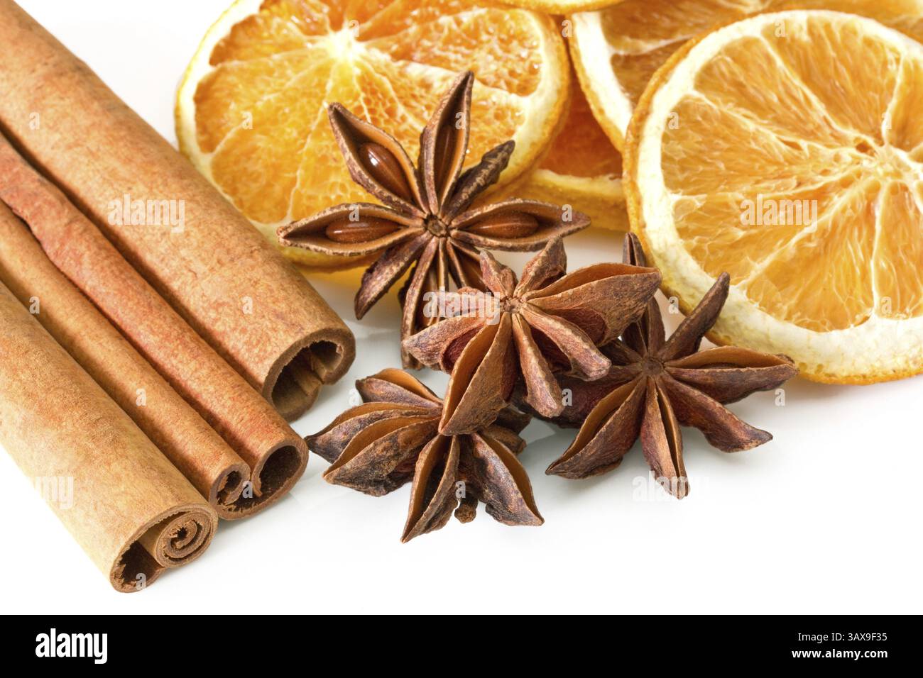 Bastoncini di cannella, stelle di anice e fette arancioni su sfondo bianco bastoncini di cannella, stelle di anice e fette arancioni su sfondo bianco Foto Stock